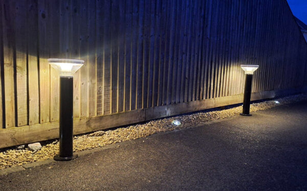 Solar powered bollar lights on footpath with wooden fence in the background